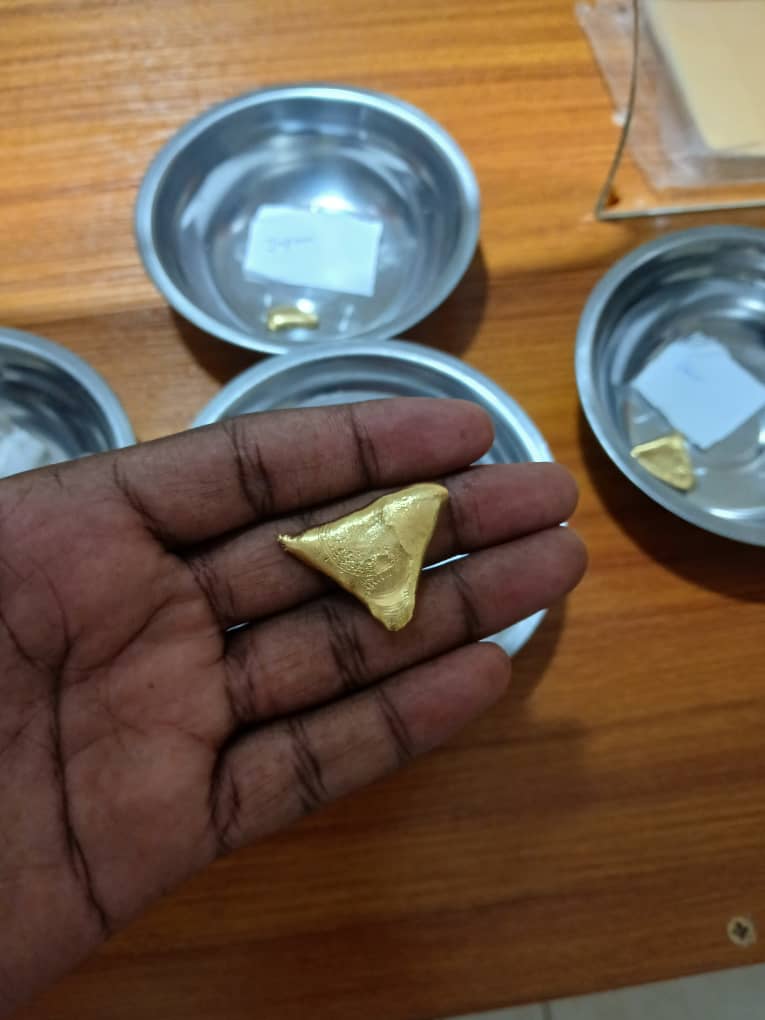 Gold doré button held in an open hand above labelled steel dishes